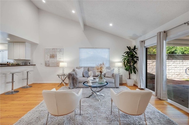 living room featuring high vaulted ceiling, a textured ceiling, and light wood-type flooring