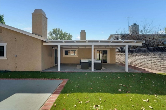 back of house featuring an outdoor living space, a patio area, and a lawn