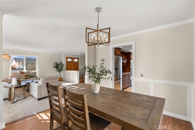 dining area with a notable chandelier, light hardwood / wood-style flooring, and ornamental molding