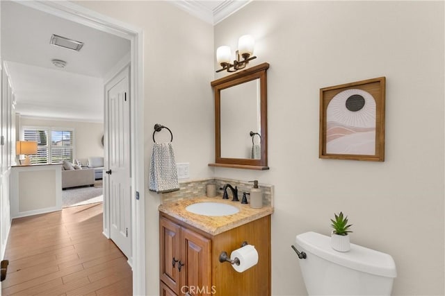 bathroom with vanity, wood-type flooring, ornamental molding, and toilet