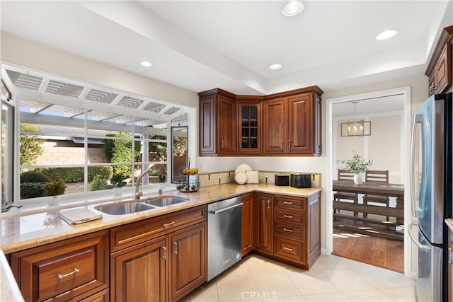 kitchen with light tile patterned flooring, sink, light stone counters, pendant lighting, and stainless steel appliances