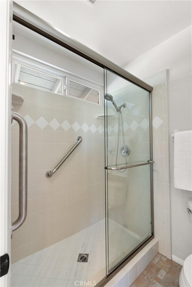 bathroom with a shower with door and toilet