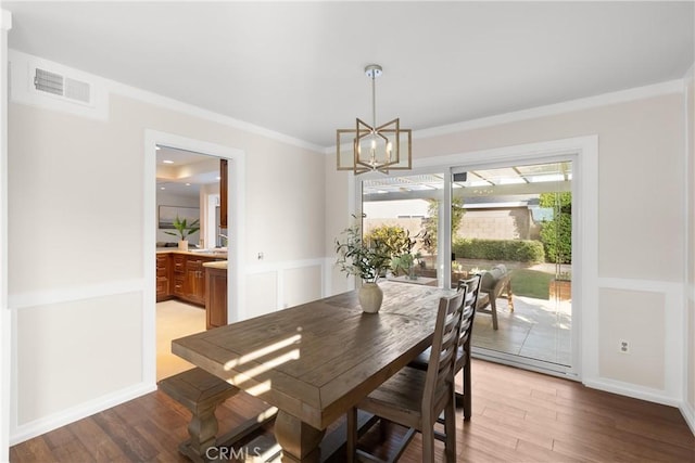 dining area with an inviting chandelier, ornamental molding, and light wood-type flooring