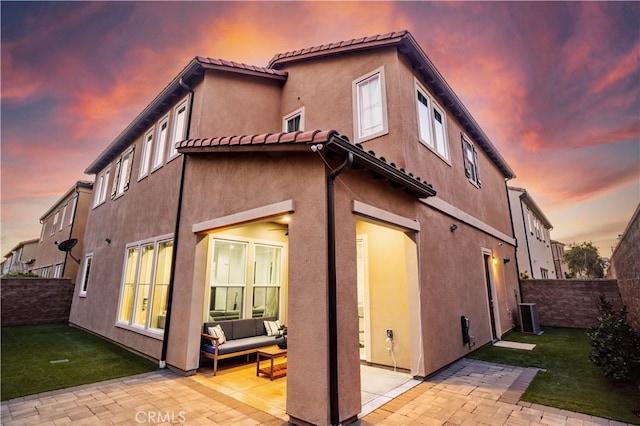 rear view of property featuring a patio, fence, an outdoor living space, a lawn, and stucco siding