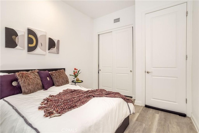 bedroom with light hardwood / wood-style floors and a closet