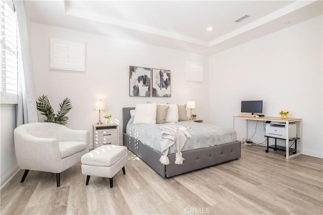 bedroom featuring a raised ceiling and light hardwood / wood-style flooring