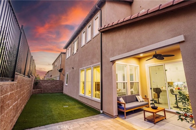 back house at dusk with a patio and ceiling fan