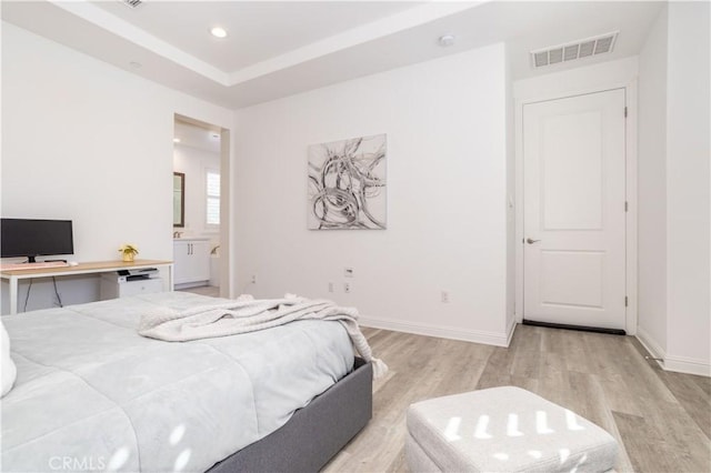 bedroom with ensuite bathroom and light hardwood / wood-style flooring