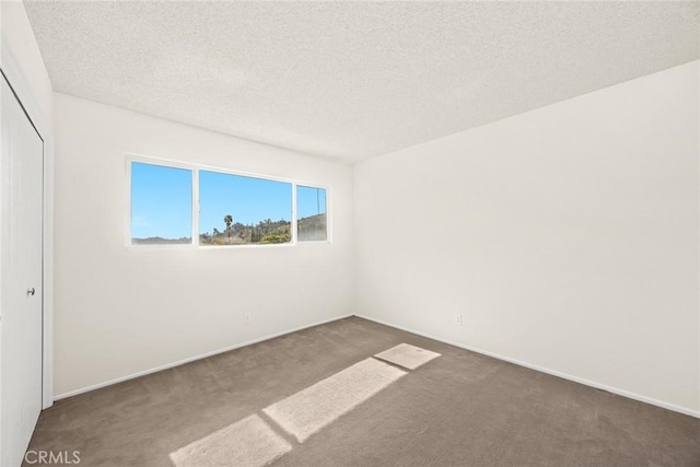 empty room with a textured ceiling and dark colored carpet