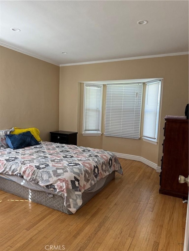 bedroom featuring crown molding and light hardwood / wood-style flooring