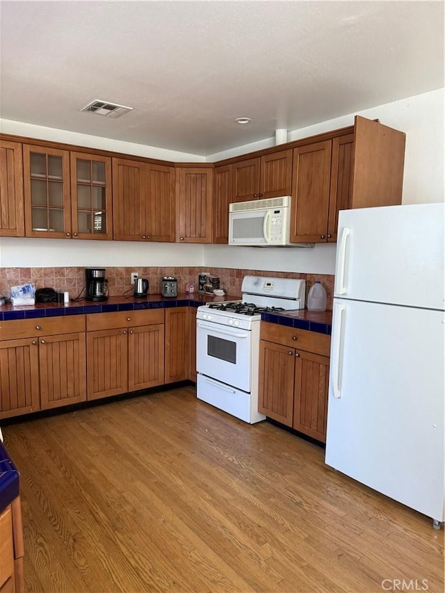 kitchen featuring light hardwood / wood-style flooring, white appliances, and tile countertops