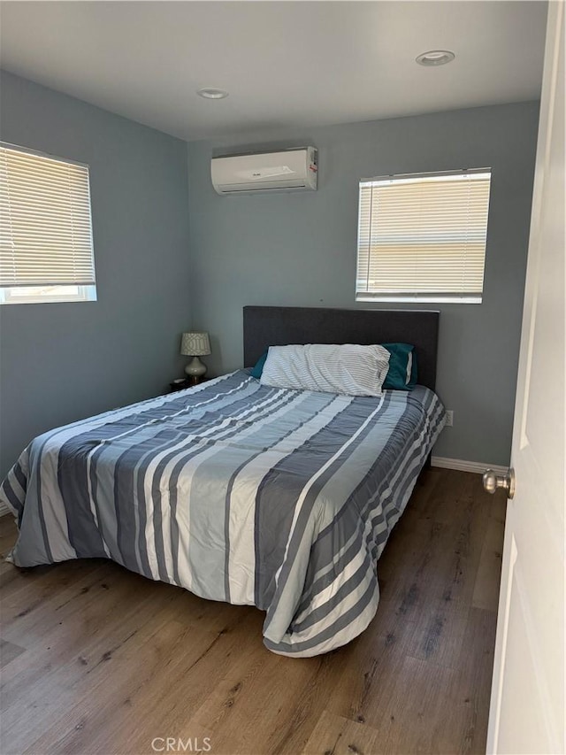 bedroom with wood-type flooring and an AC wall unit