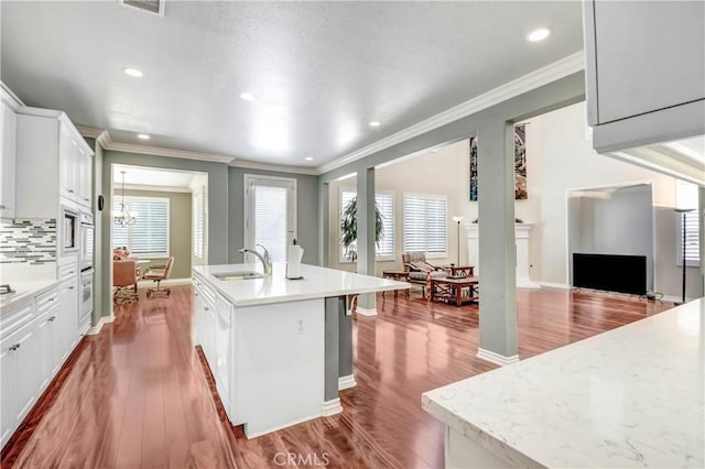 kitchen with white cabinetry, sink, hardwood / wood-style flooring, and a center island with sink