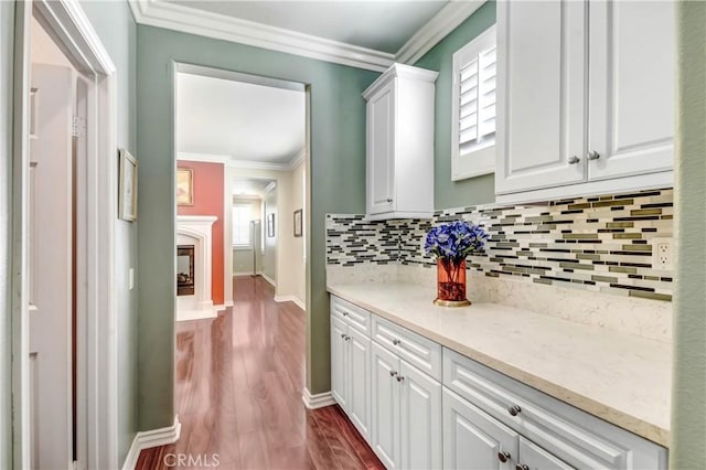 kitchen featuring crown molding, dark hardwood / wood-style flooring, light stone countertops, and white cabinets