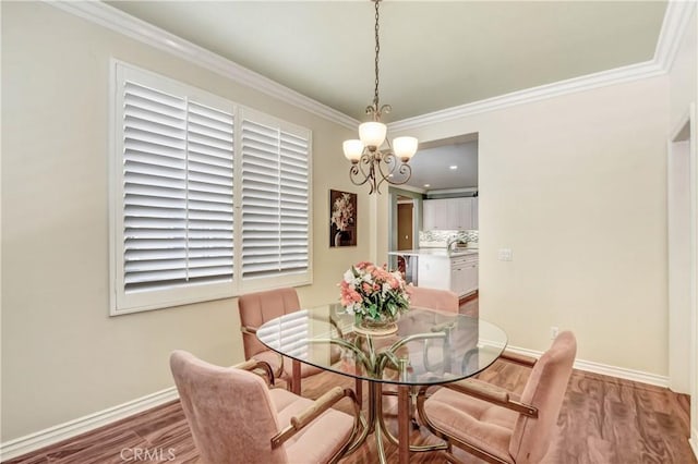 dining area featuring wood-type flooring, a notable chandelier, and crown molding