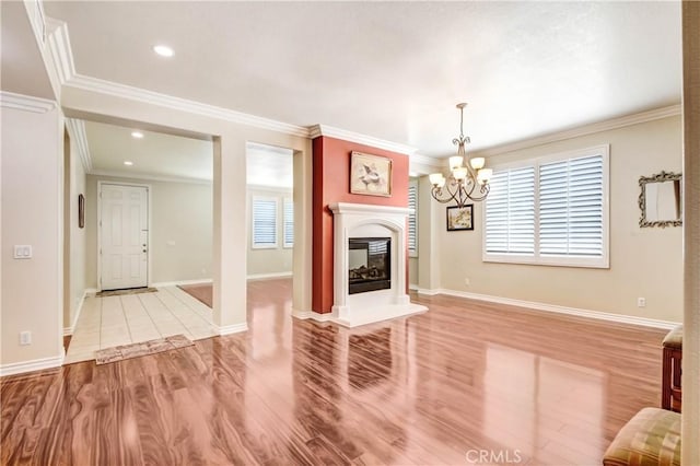 unfurnished living room featuring crown molding, a chandelier, and light hardwood / wood-style flooring