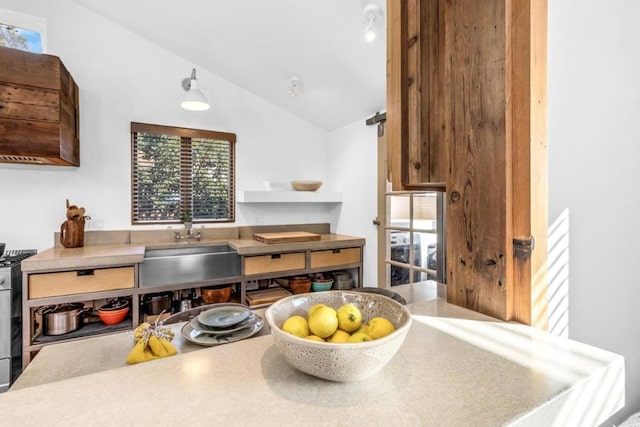 kitchen with lofted ceiling, sink, and range