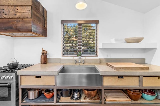 kitchen featuring lofted ceiling, sink, and stainless steel gas range oven