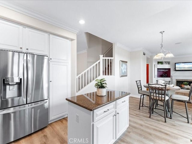 kitchen featuring a center island, stainless steel fridge with ice dispenser, light wood-type flooring, dark stone counters, and white cabinets