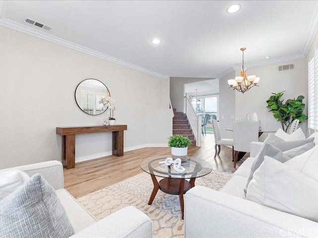 living room featuring ornamental molding, a chandelier, and light hardwood / wood-style floors