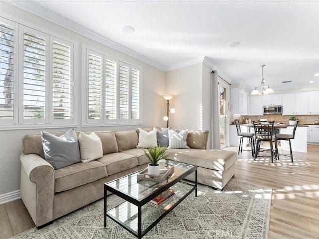 living room featuring crown molding, light hardwood / wood-style flooring, and a chandelier