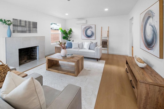 living room with a wall mounted air conditioner, a fireplace, and light hardwood / wood-style floors