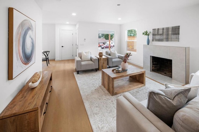 living room with a tiled fireplace and light hardwood / wood-style flooring