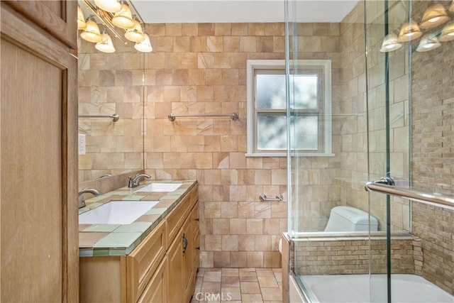 bathroom featuring vanity, bath / shower combo with glass door, and tile walls