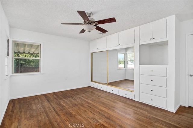 unfurnished bedroom featuring ceiling fan, dark hardwood / wood-style floors, a textured ceiling, and a closet