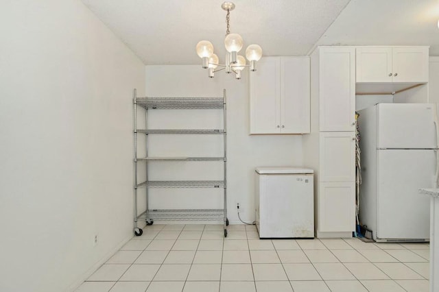 interior space featuring hanging light fixtures, fridge, white cabinets, and white fridge