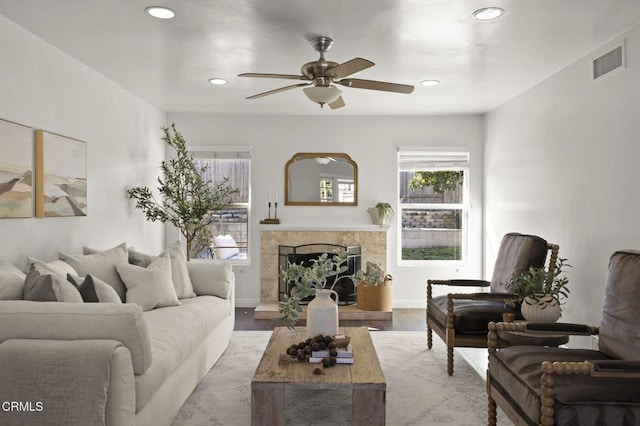 living room featuring a tiled fireplace, light hardwood / wood-style floors, and ceiling fan