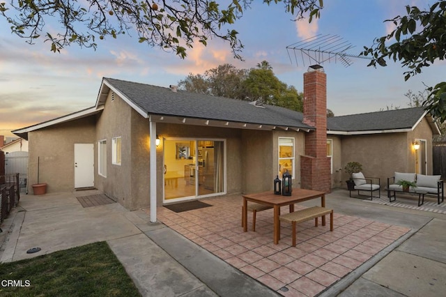 back house at dusk featuring a patio