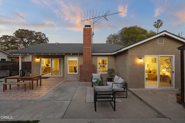 back house at dusk featuring outdoor lounge area and a patio area