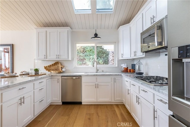 kitchen featuring white cabinetry, appliances with stainless steel finishes, a skylight, and sink