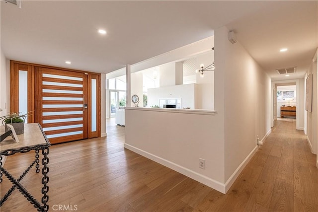 corridor with floor to ceiling windows, a notable chandelier, and light hardwood / wood-style floors