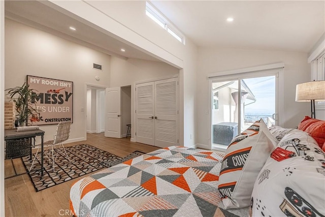 bedroom featuring hardwood / wood-style flooring, high vaulted ceiling, and a closet