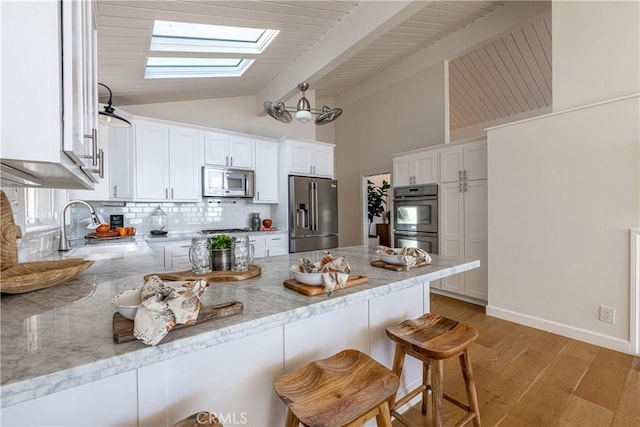 kitchen with a breakfast bar, white cabinetry, sink, kitchen peninsula, and stainless steel appliances