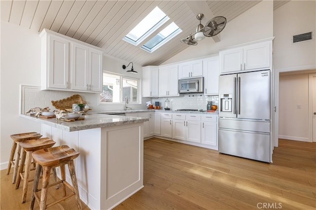 kitchen featuring appliances with stainless steel finishes, white cabinets, and light stone counters