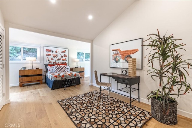 bedroom with high vaulted ceiling, light hardwood / wood-style floors, and multiple windows