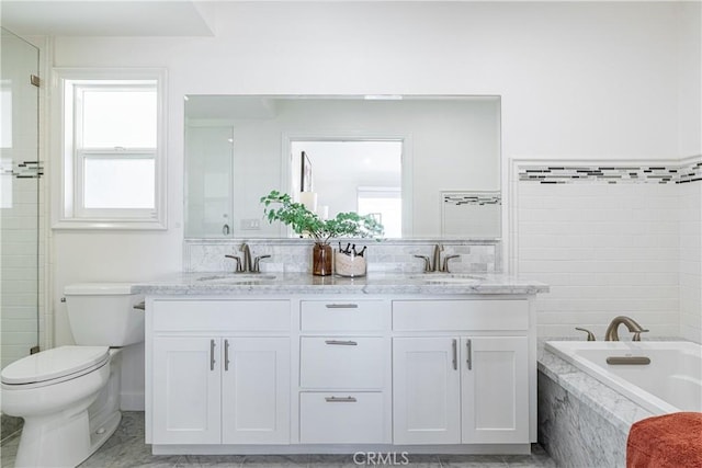 bathroom featuring vanity, tiled tub, and toilet