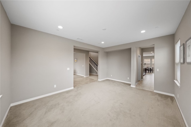 unfurnished room featuring baseboards, recessed lighting, stairway, and light carpet