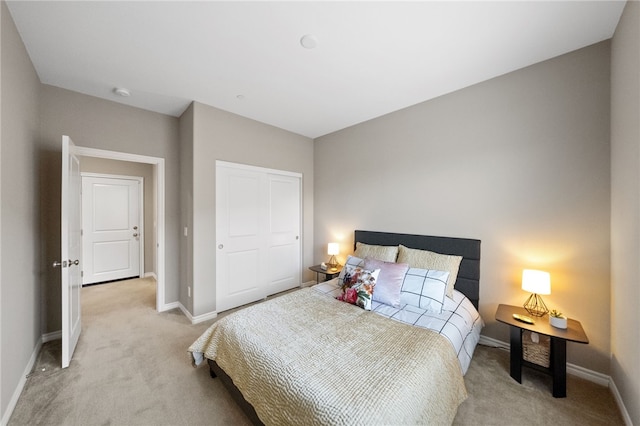 bedroom featuring baseboards, a closet, and light colored carpet