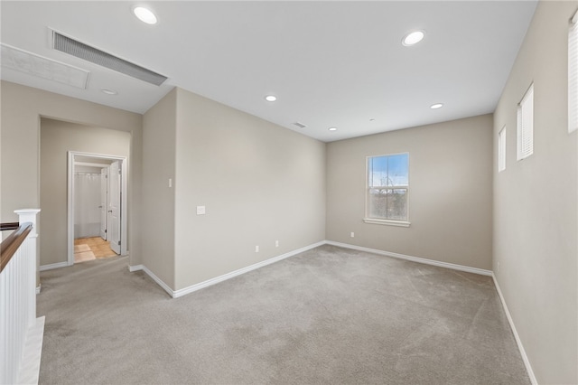 spare room with baseboards, visible vents, recessed lighting, and light carpet