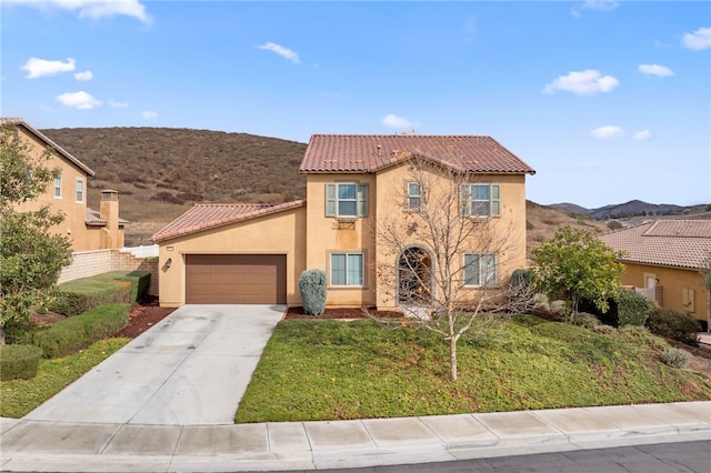 mediterranean / spanish home featuring a tiled roof, an attached garage, concrete driveway, a front lawn, and stucco siding
