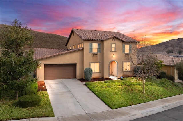 mediterranean / spanish house featuring a garage, a mountain view, and a lawn