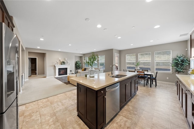 kitchen with an island with sink, appliances with stainless steel finishes, sink, and dark brown cabinetry