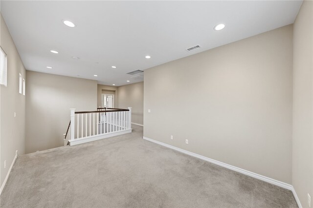carpeted empty room with baseboards, visible vents, and recessed lighting