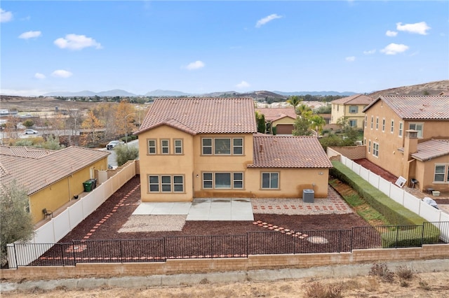 mediterranean / spanish-style house featuring a fenced backyard, stucco siding, a patio area, and a mountain view