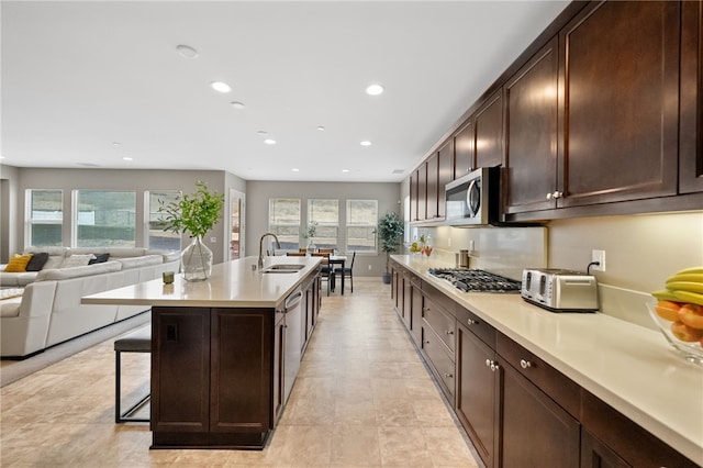 kitchen featuring sink, a breakfast bar area, a kitchen island with sink, dark brown cabinets, and stainless steel appliances