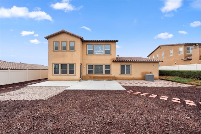 rear view of property with stucco siding, a fenced backyard, and a patio